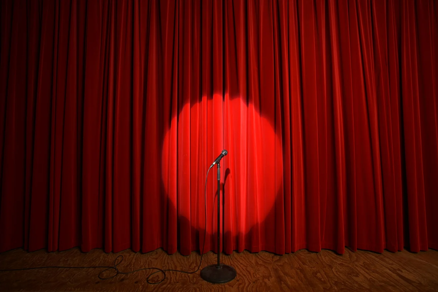 Escenario vacío con micrófono bajo un spotlight, esperando al próximo comediante
